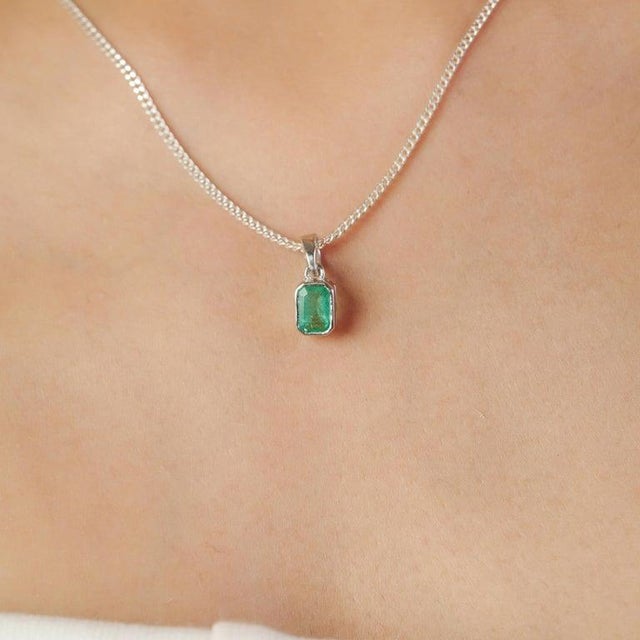 This refined Emerald pendant, totaling 0.57 carats, is elegantly set in a smooth bezel and crafted from 925 Sterling...