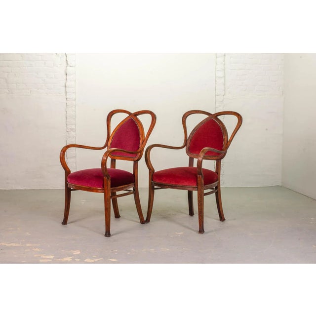 Elegant French pair of heart shaped side chairs. The wooden structured frame is upholstered with a red velvet seating and...