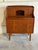 An elegant multi-functional form combines an adjustable pull-out writing surface with a hidden vanity mirror layout. The...