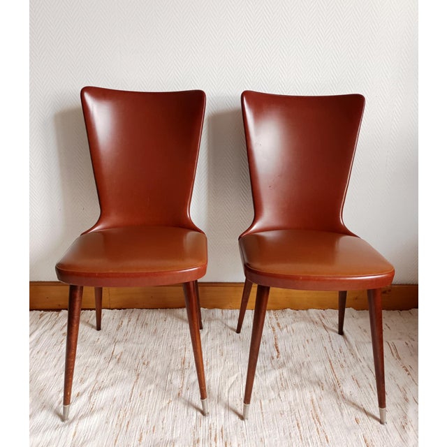 Pair of vintage chairs, circa 1960 Pair of tan vinyl chairs with splayed legs and rings on the front feet. The tapered...