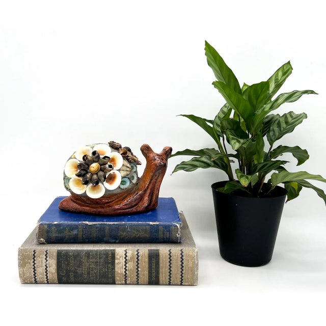 Whimsical and coastal, this vintage folk art snail figurine is crafted from red painted cement and adorned with real...