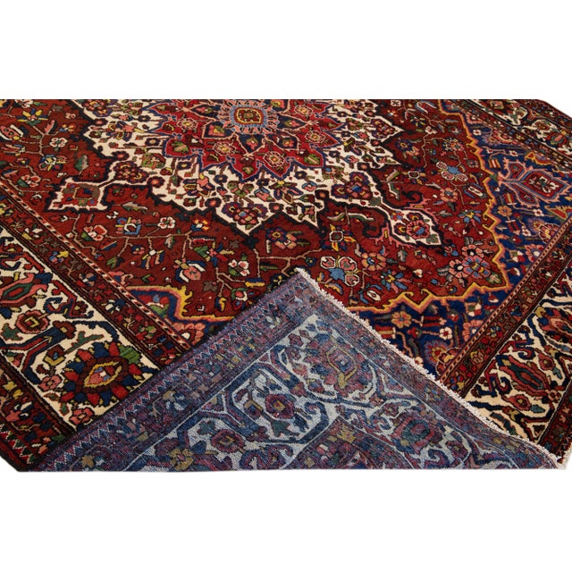 Beautiful Antique Bakhtiari hand-knotted wool rug with a red field. This Persian piece has an all-over multicolor accent...