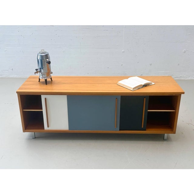 This exceptional swiss sliding-door sideboard from the 1950s/60s impresses with its clean, functional design and the...