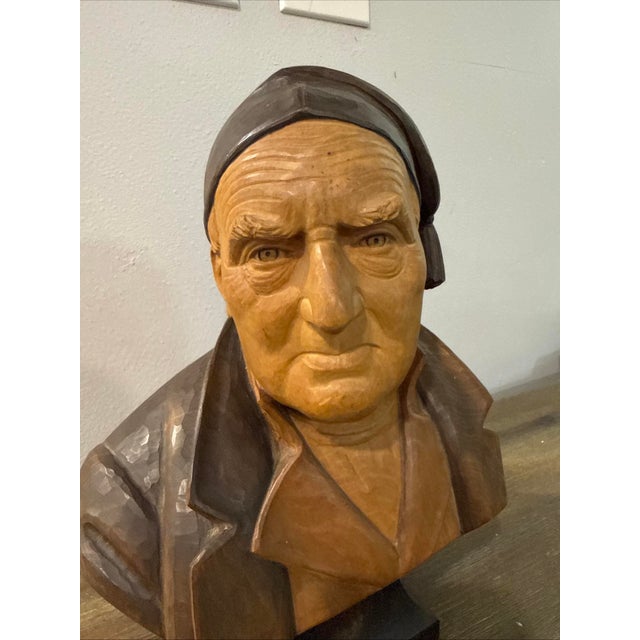 A hand-carved linden wood bust depicting an elderly man with detailed facial features and a distinctive cap.. Please...