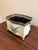 A charming vintage tole cachepot featuring a softly aged cream finish adorned with hand-painted blue tulips in an urn...