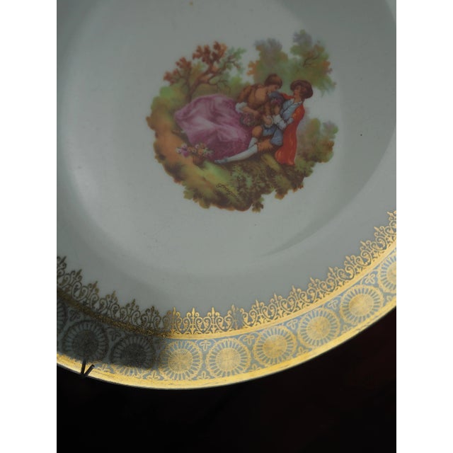 Plate with gallant scene, couple in love in the middle of nature. Large intricate golden border. Metal hook. This plate is...