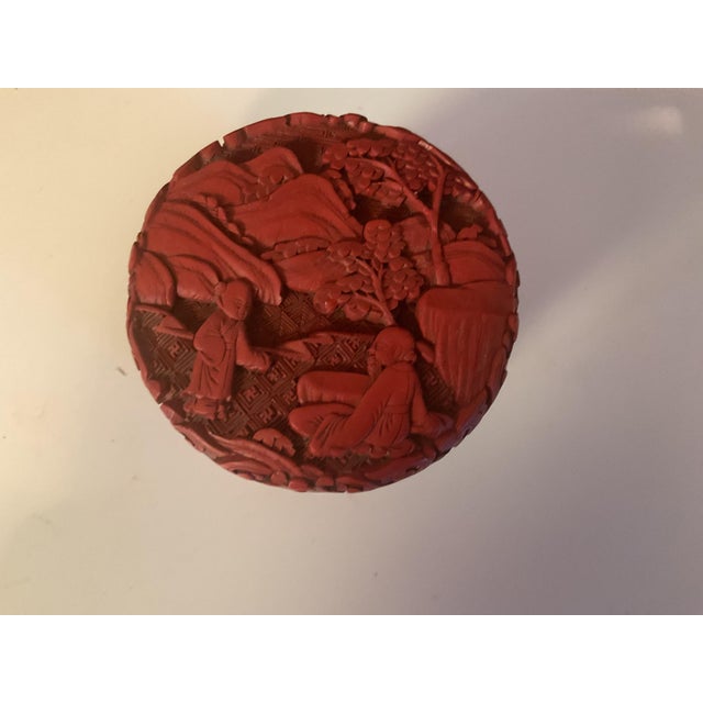 A beautifully carved Chinese cinnabar lacquer box featuring intricate floral and scroll motifs in classic deep red...