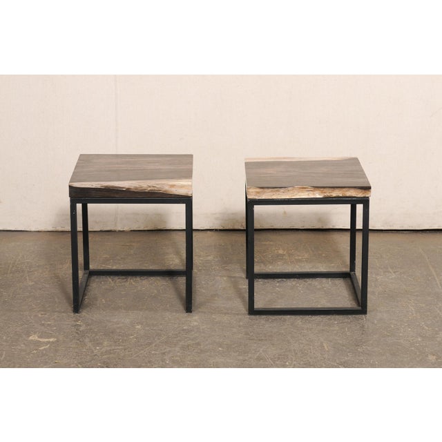 A pair of sleekly designed custom petrified wood top side tables. This pair of tables each feature a square-shaped...