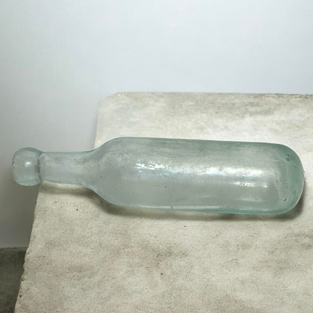 Antique late-19th-century aqua glass bottle with a distinctive rounded base, elongated neck, and substantial blob-style...