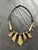 Vintage tribal-inspired necklace featuring shield shaped pendants with exaggerated geometric tapering, interspersed with...