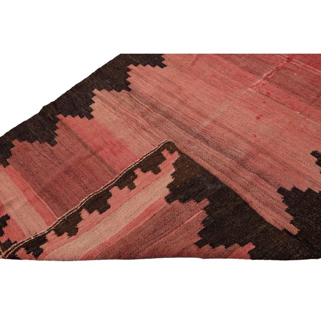 Beautiful kilim handmade wool runner with a red field. This Vintage flatweave rug has a brown accent features a gorgeous...