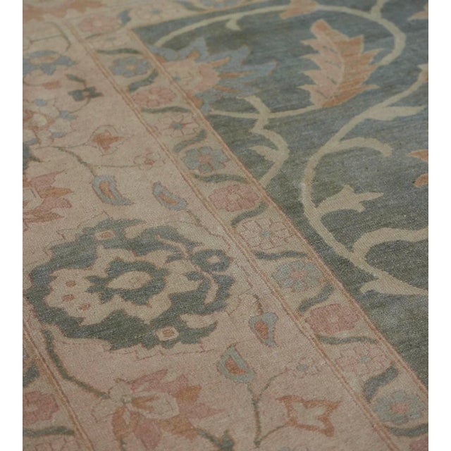 This antique handwoven Amritsar rug features a sage green field with a ivory, light coral, pale blue, and buff-brown...