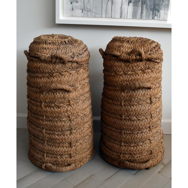 Set (2) of rare olive collection vessels from Spain. These antique pieces stand over 2' tall, featuring tightly woven wicker.