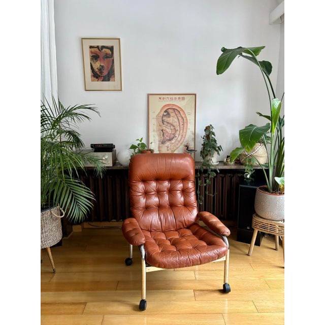 Leather armchair on casters, Sweden, 1970s. Chrome-plated metal, brown-red leather upholstery, and cotton upholstery on...