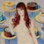 Angel Food by Suzy Smith | Oil on Panel Portrait of a woman with cakes in the background For Sale