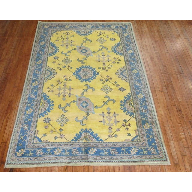 An antique Turkish Oushak with an unusual bright sunny yellow ground outlined by teal border. Measure: 6'1" x 9'9".