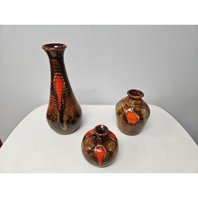 A set of three stunning Dryden Pottery vases with a high-gloss brown, green, and bright burnt orange/red drip glaze. Based...