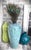 This sculptural ceramic vase features an elegantly tapered form and a luminous, high-gloss glaze inspired by the blues and...