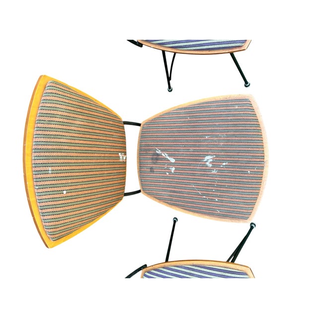 A set of three mid-20th century plywood dining or side chairs with padded seats and backs and black wrought iron frames in...