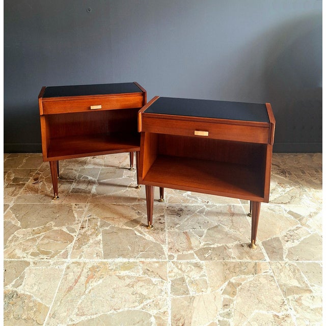 Pair of teak bedside tables with black painted glass shelf made in Italy in the 1960s. The bedside tables have a drawer in...