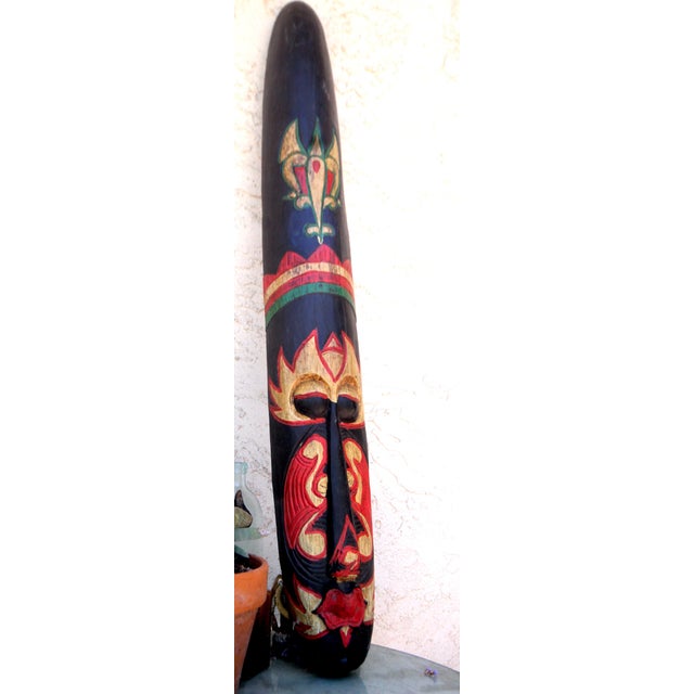 A hand-carved Indonesian wood mask, originating from the late 20th century, serves as an exceptional statement piece in a...