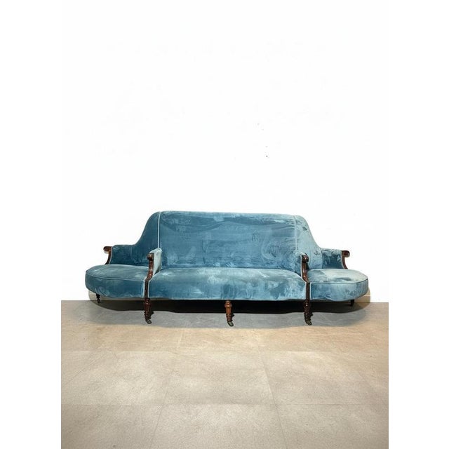 A stunning antique Victorian-style sofa upholstered in a soft, rich blue velvet. This impressive piece features elegant...