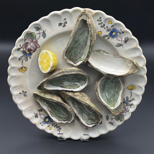 This is a trompe-l'œil French faience oyster plate with six molded, hand-painted oyster shells and a lemon wedge fixed to...