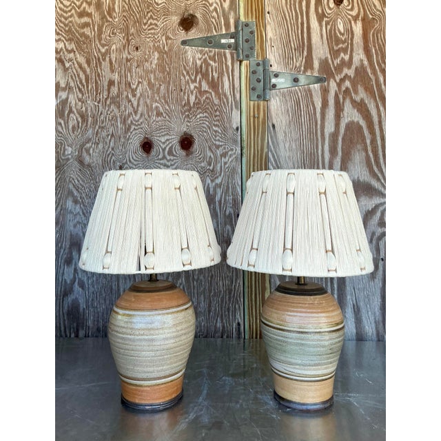 Radiating with the warm, artisanal spirit of the 1970s, this phenomenal pair of vintage studio pottery lamps is a...