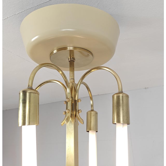 Chandelier from a Cinema from the 1920s, featuring a solid brass frame with four tubular light arms and an laquered,...
