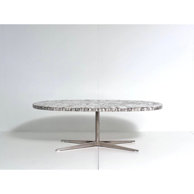 The tabletop is composed of numerous irregularly cut stone segments, their white base color traversed by striking gray to...