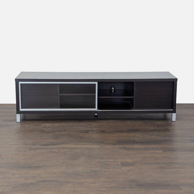 This sleek black entertainment center features a modern design with a glass front sliding door and metal trim. It has four...