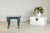 A striking bronze table with a rich verdigris patina and black marble top, its design marked by bold sculptural detail and...