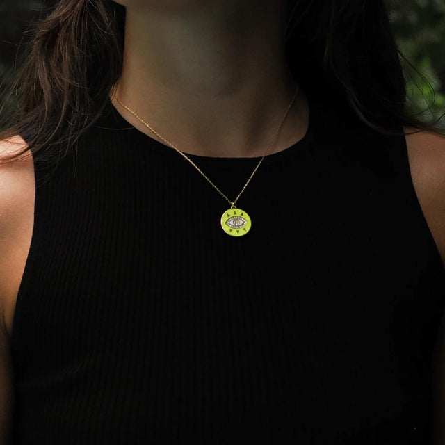Brighten your day with the Cheerful Neon Yellow Evil Eye & Diamond Pendant Gold Chain Necklace. This playful pendant,...