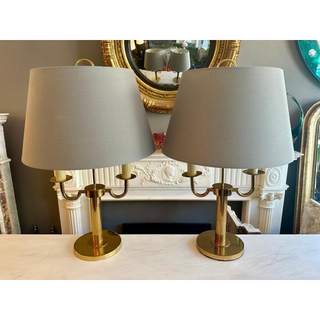 A pair of Mid 20th century Gilt Brass Bouliotte style table lamps with new grey fabric shades. The circular plinth base...
