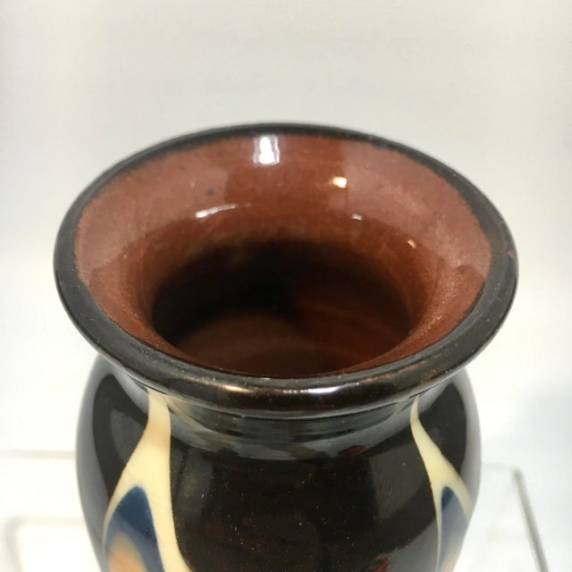 This vase is glazed in swirls of mustard yellow, ivory, ink blue, brown, and oxblood red. Dimensions: 2.425” x 2.425” x...