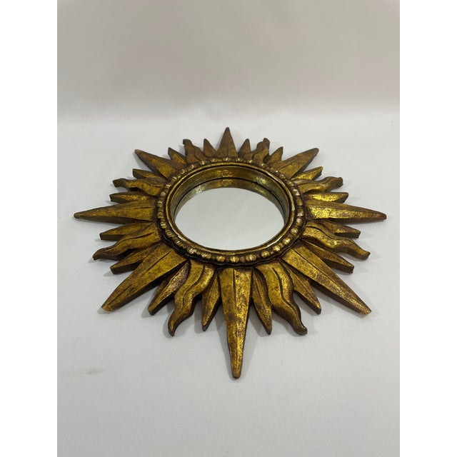 A stunning Mid Century Modern gilded resin Sunburst Accent Wall Mirror with varying lengths of rays. Circa Mid 20th...
