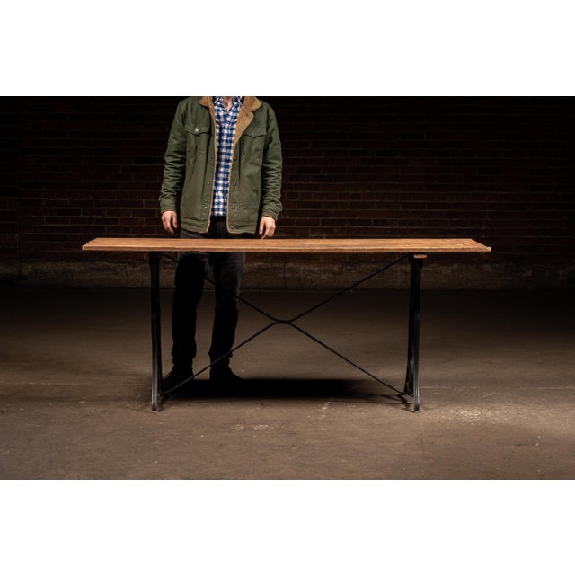 Industrial worktable constructed from a long two-board oak plank top mounted to a repurposed cast iron treadle-style base....