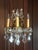 These beautiful 1920's brass and crystal sconces have decorative scrolls with acanthus leaves coming out of a tulip base....