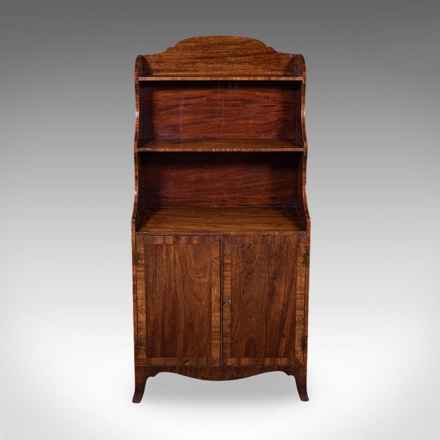 This is an antique waterfall bookcase. An English, flame mahogany petite chiffonier, dating to the Georgian period, circa...