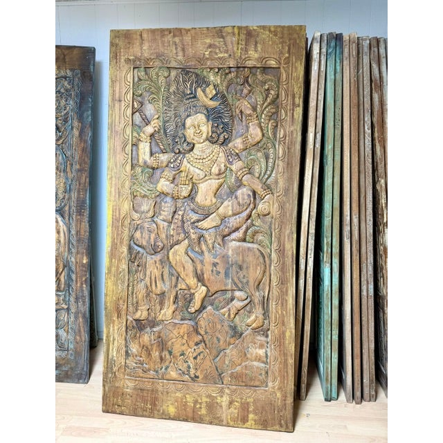 A striking hand-carved wooden panel from India, featuring intricately detailed relief carvings of Hindu deities, believed...