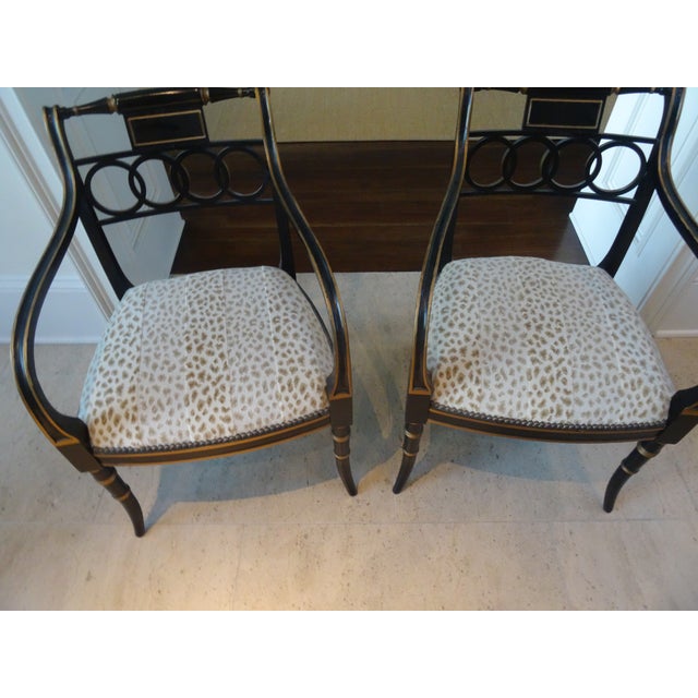 A Pair of Baker Governor Alastor Chairs gold painted and ebonized armchairs. The Chairs boast new upholstery with nailhead...