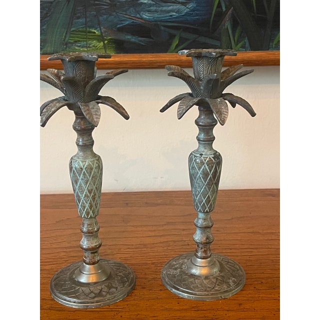 A charming pair of vintage pineapple-form candlesticks with layered palm fronds and naturally aged verdigris patina. The...