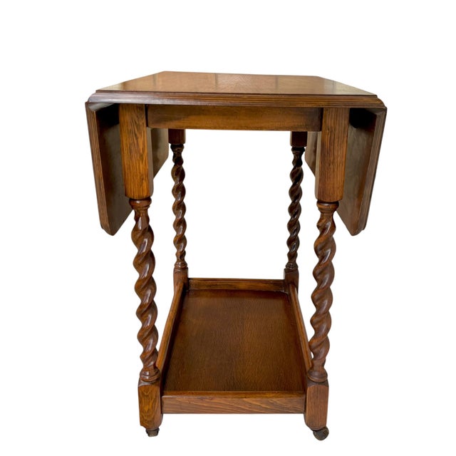 Charming antique English oak drop-leaf card table featuring beautifully turned barley-twist legs and a warm, richly aged...