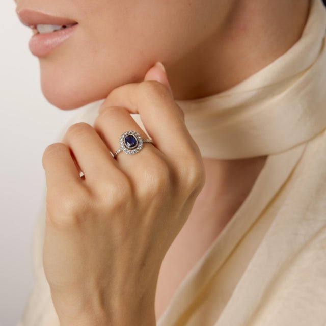 A refined homage to 1930s glamour, this Art Deco–inspired cluster ring centers on a vivid 0.79 carat cushion cut sapphire....