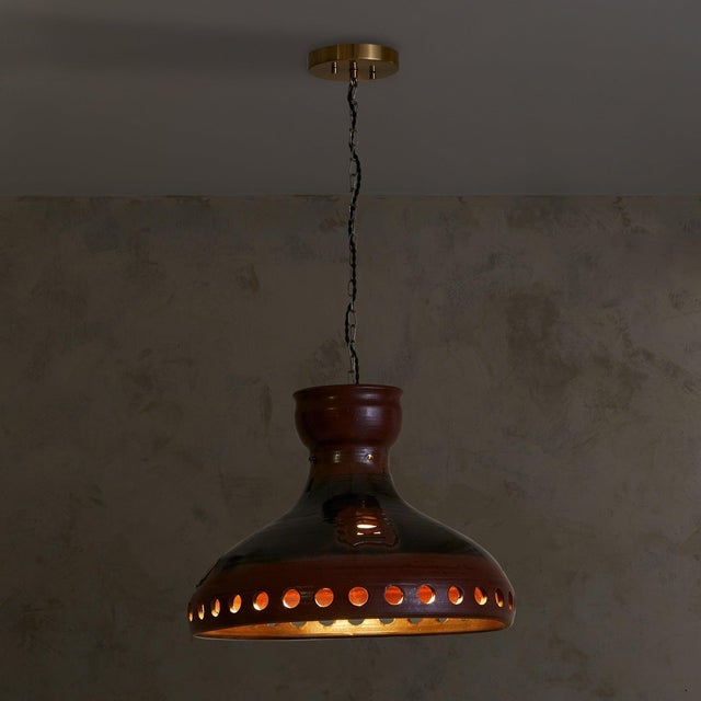 A 1960s Danish ceramic pendant with a wide, hand-thrown silhouette finished in deep maroon and smoky charcoal glaze. The...