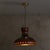 A 1960s Danish ceramic pendant with a wide, hand-thrown silhouette finished in deep maroon and smoky charcoal glaze. The...