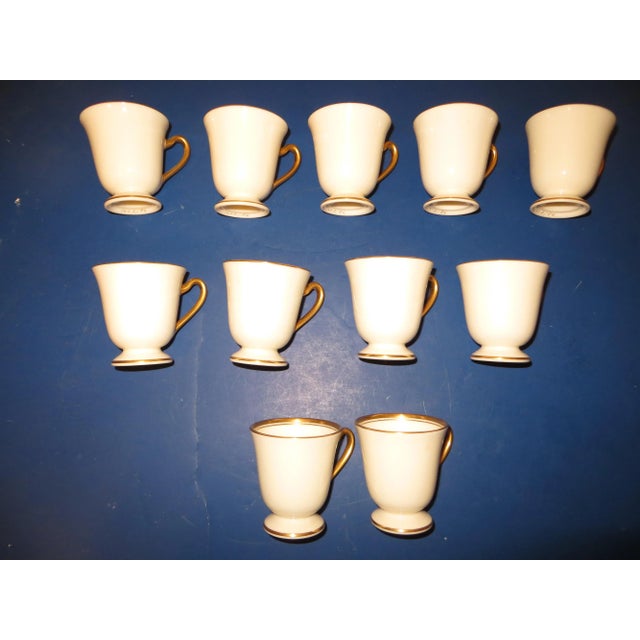 Available for purchase is a very beautiful set of 11 coffee cups and 12 Saucers with gold trim, made by and marked ; Lenox...