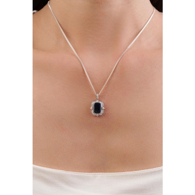 This Art Deco-inspired pendant features a striking 3.4 carat natural blue sapphire, set in 14k white gold. The center...