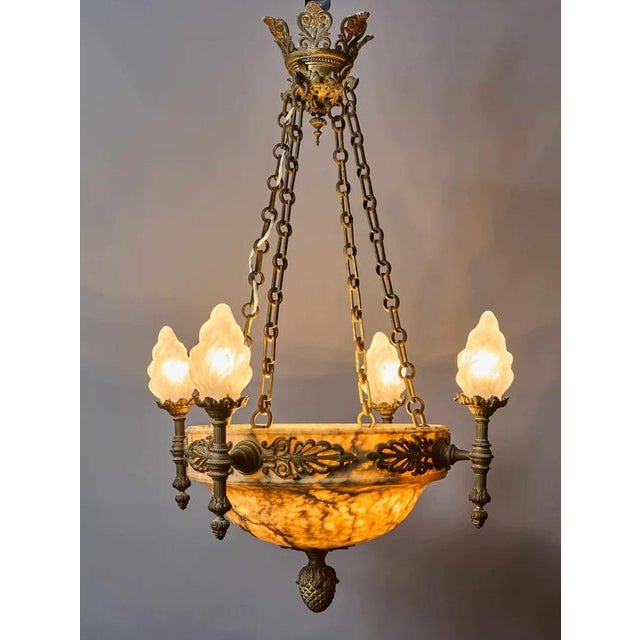 The bronze chandelier with an alabaster bowl and torch lights is an exceptionally decorative light fixture from the period...