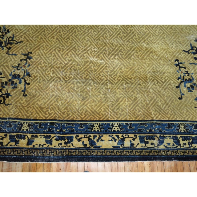 An oversize Chinese Peking rug in tans and blue. Peking rugs consist of designs that are simpler and asymmetrical, often...